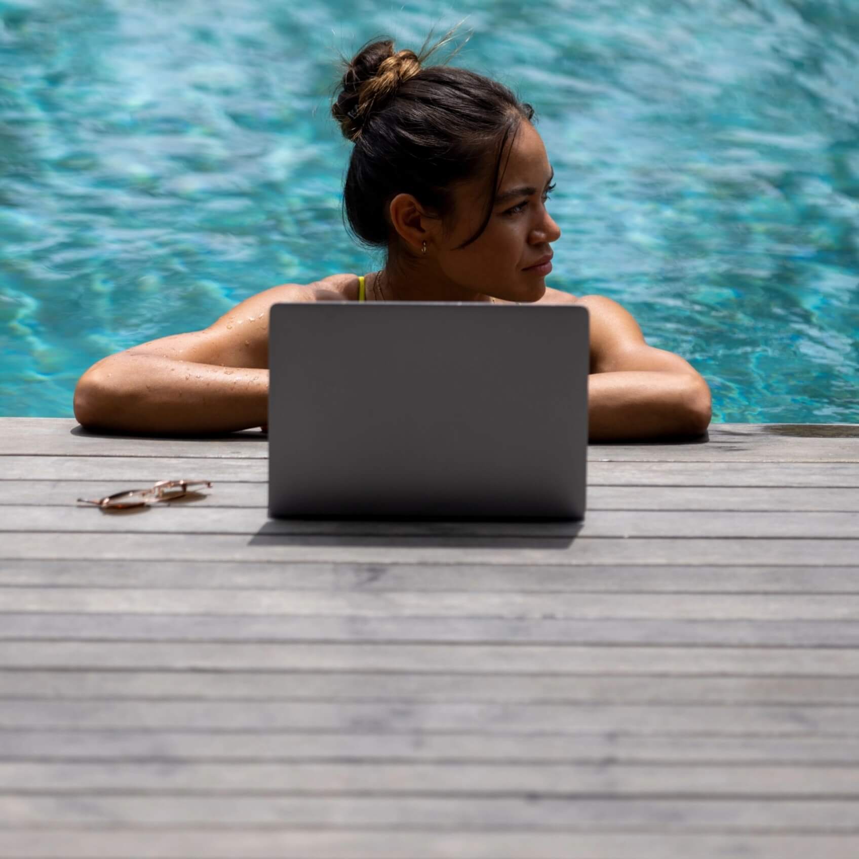 Woman in pool using laptop