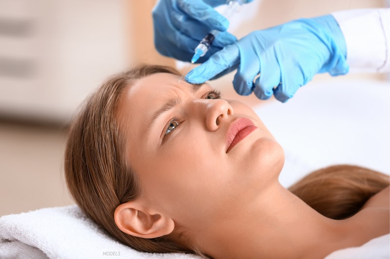 Young woman getting an injectable treatment in her frown lines between brows.